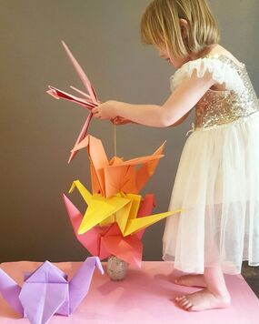 A child playing with large origami cranes